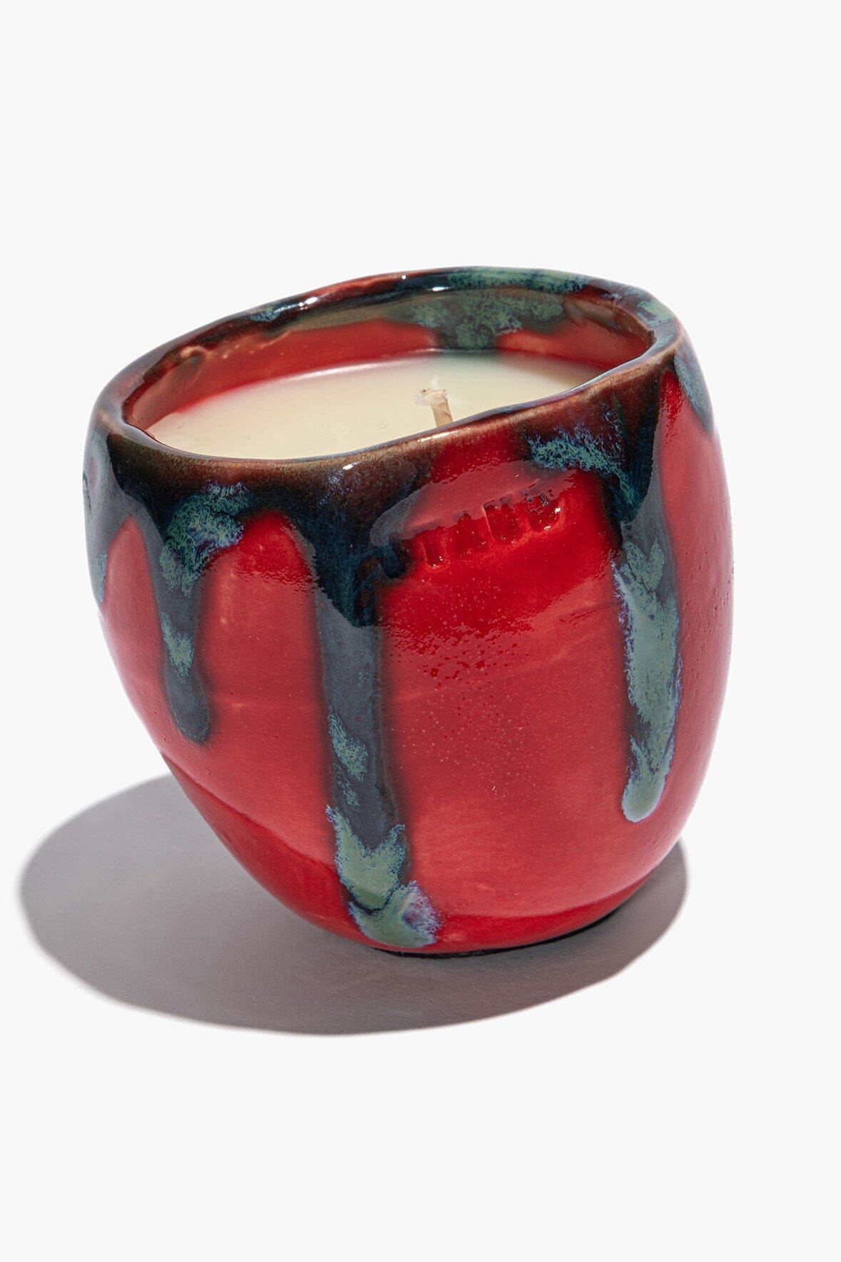 Small SERRE ceramic candle in red with teal-blue drip glaze, visible wick