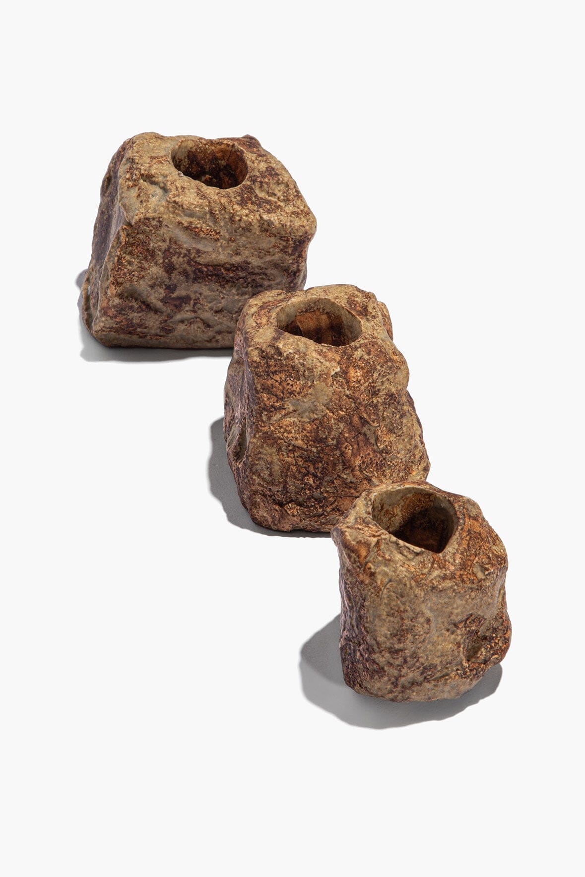 Organic rock candlestick set with three rugged stone candle holders, angled