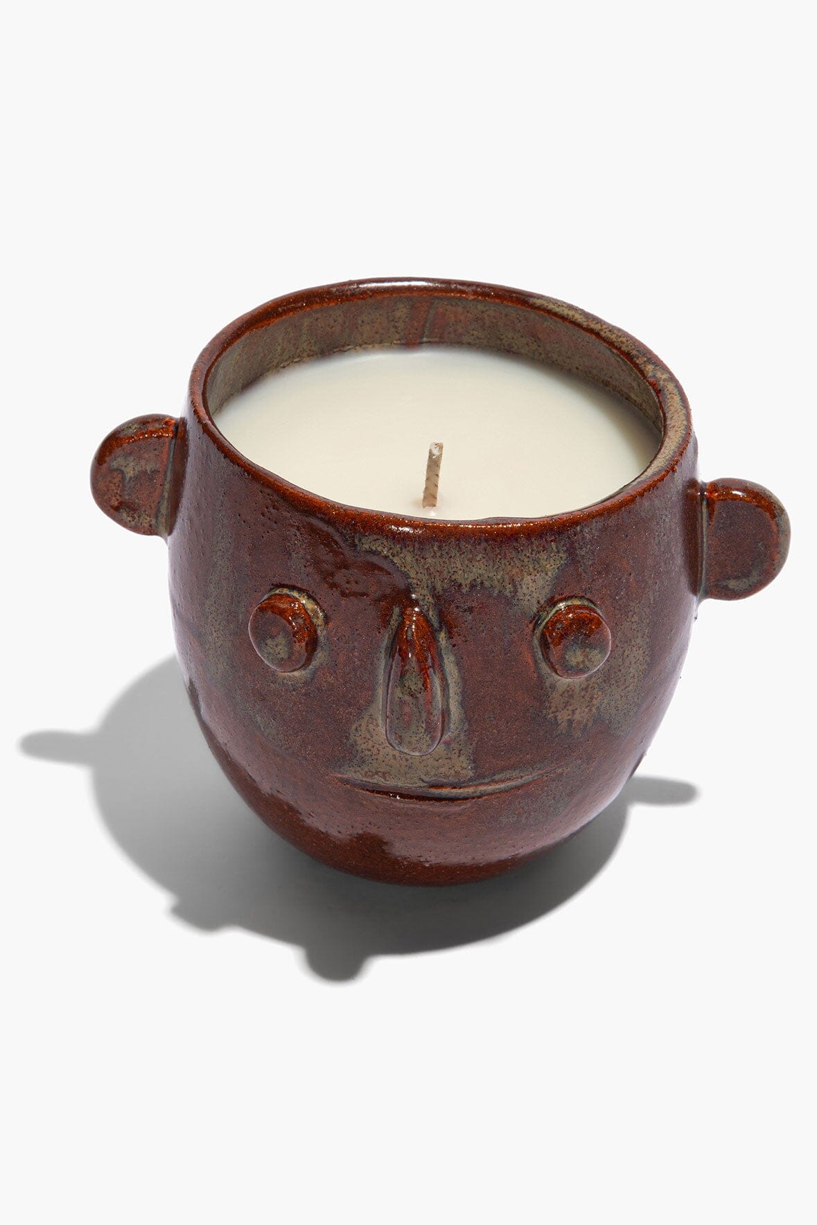 Ceramic candle pot with white wax center and small wick, brown glazed face handles