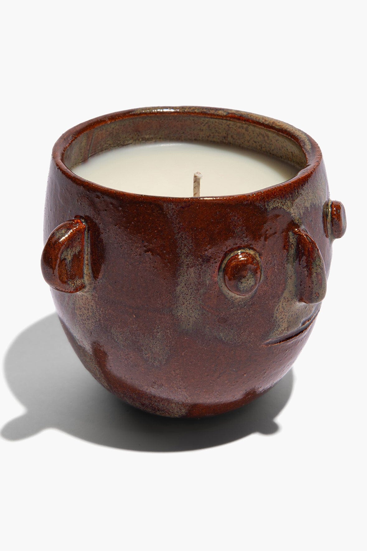 Ceramic candle pot, brown glaze with raised face details and side handles; white wax top