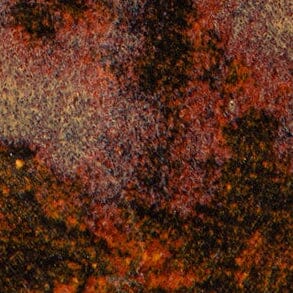Close-up of ceramic glaze texture with speckled brown, rust, and dark tones