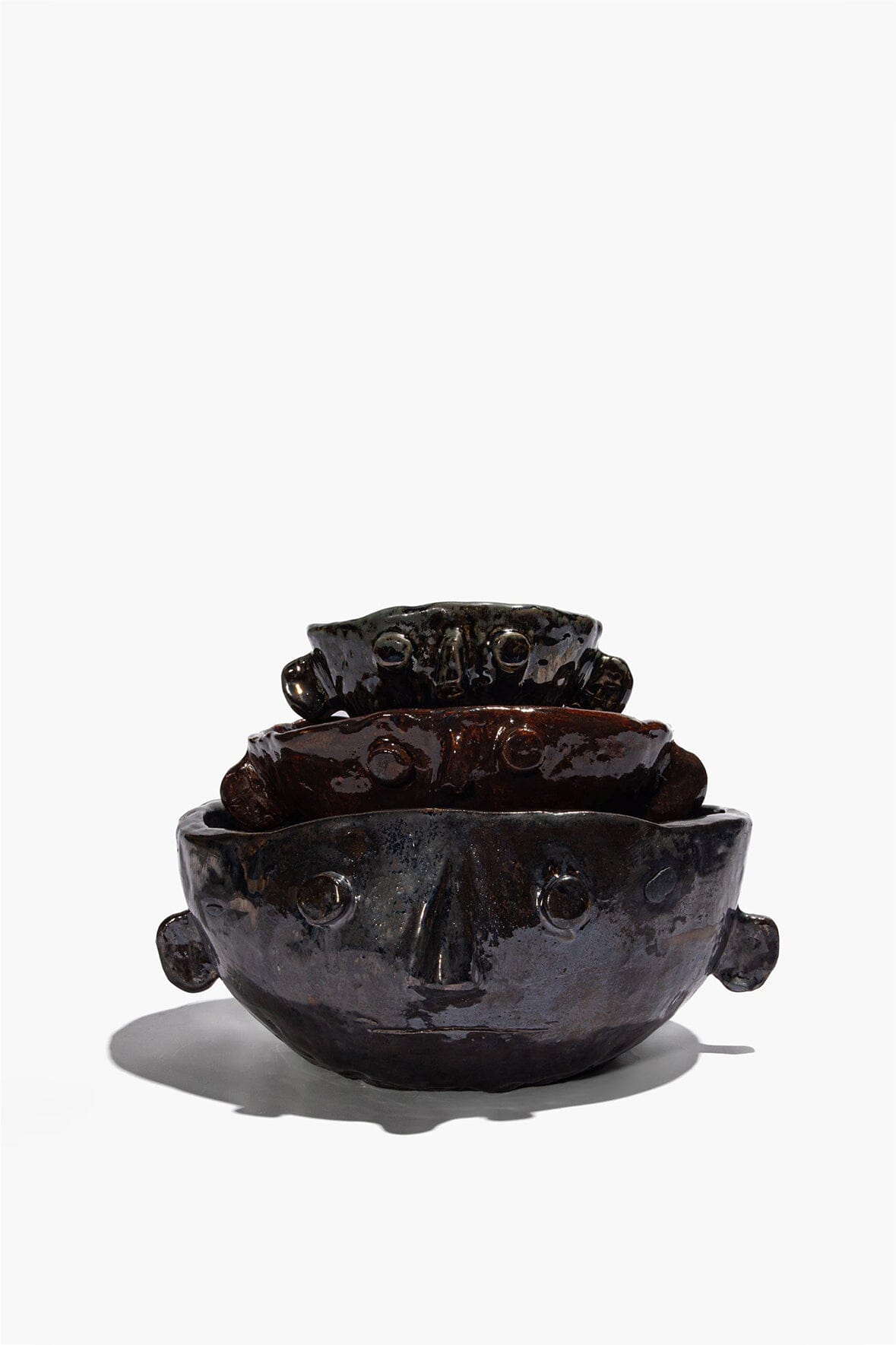 Stacked Large Henry bowls in dark glaze, showing sculpted faces and side knobs.
