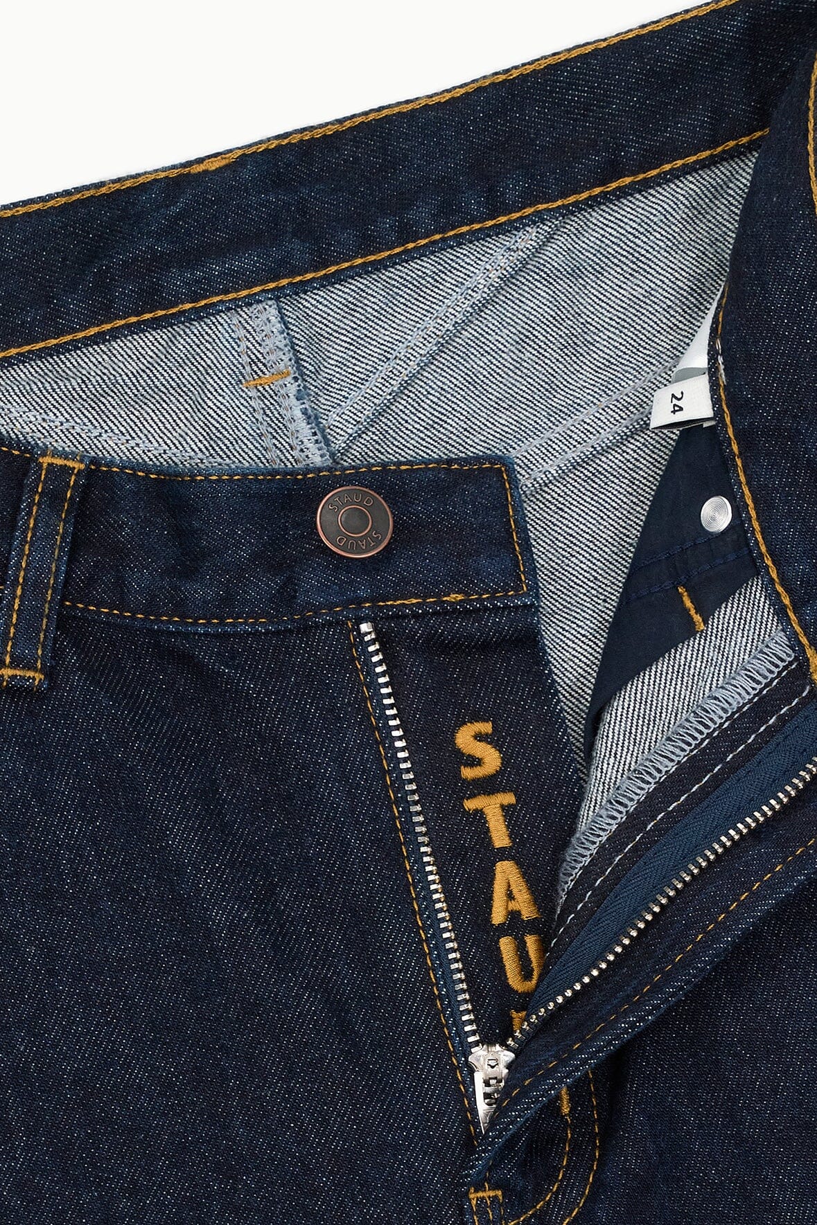 Indigo denim jeans with pocket stitching, coin label, and button