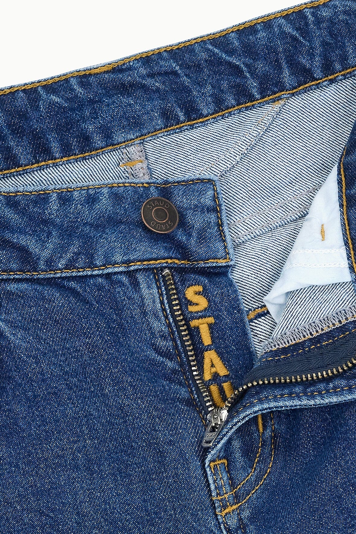 Stone blue jeans front waistband with logo button, zipper fly, and belt loops