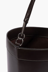 Leather bin handle detail: metal ring clasp with braided strap over dark interior.