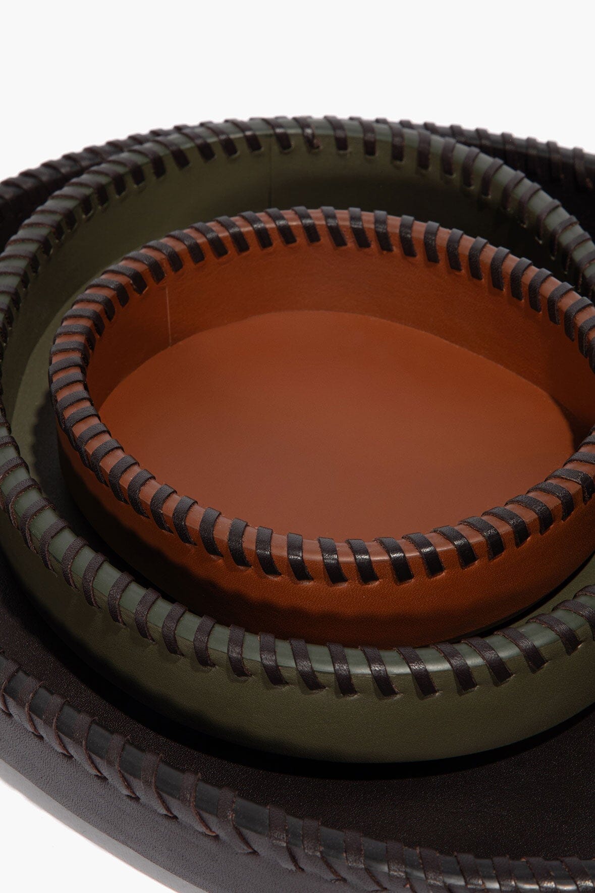 Overhead view of two nested round leather trays with orange-brown inner trays