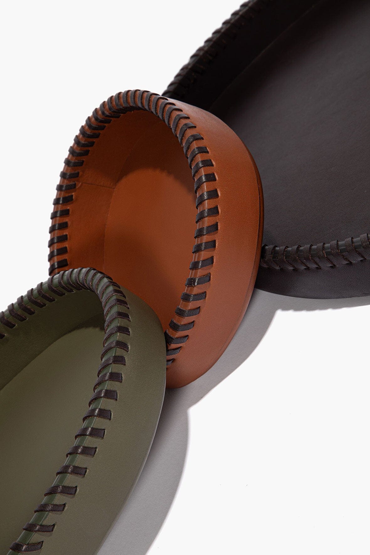 Round leather trays nested together, showing tan interior and contrast stitched edges