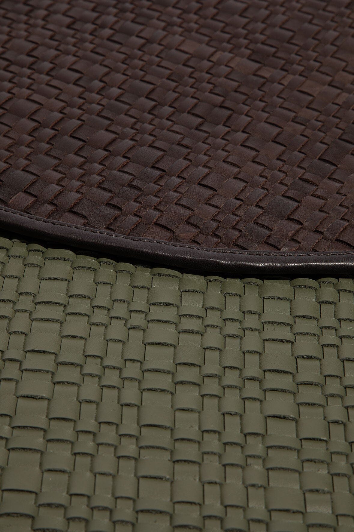 Moss green leather placemat edge with woven pattern and dark brown trim, close-up