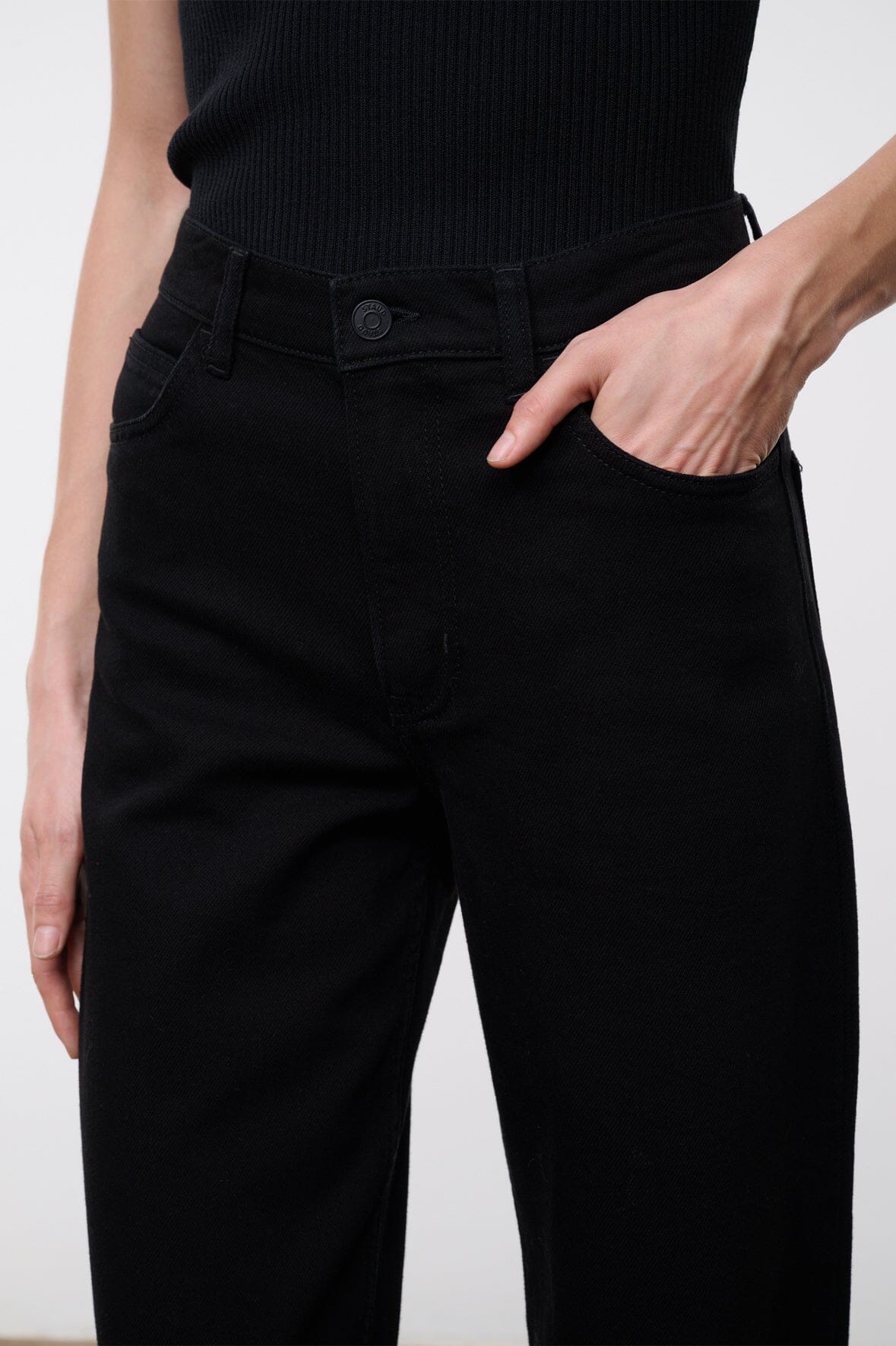 Black high-rise jeans waistband detail with button closure and belt loops