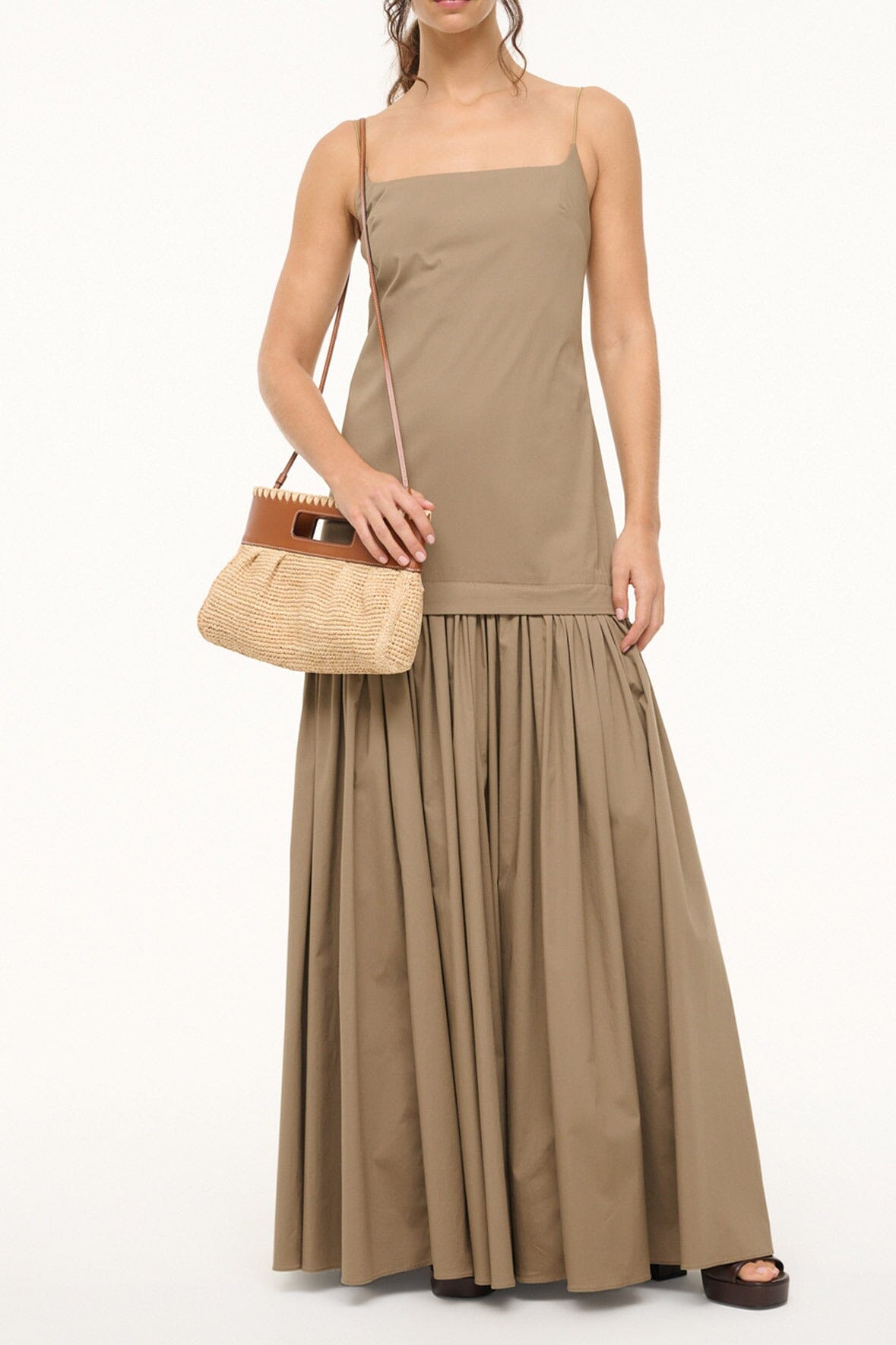 Natural tan straw clutch with brown leather flap carried with long dress.