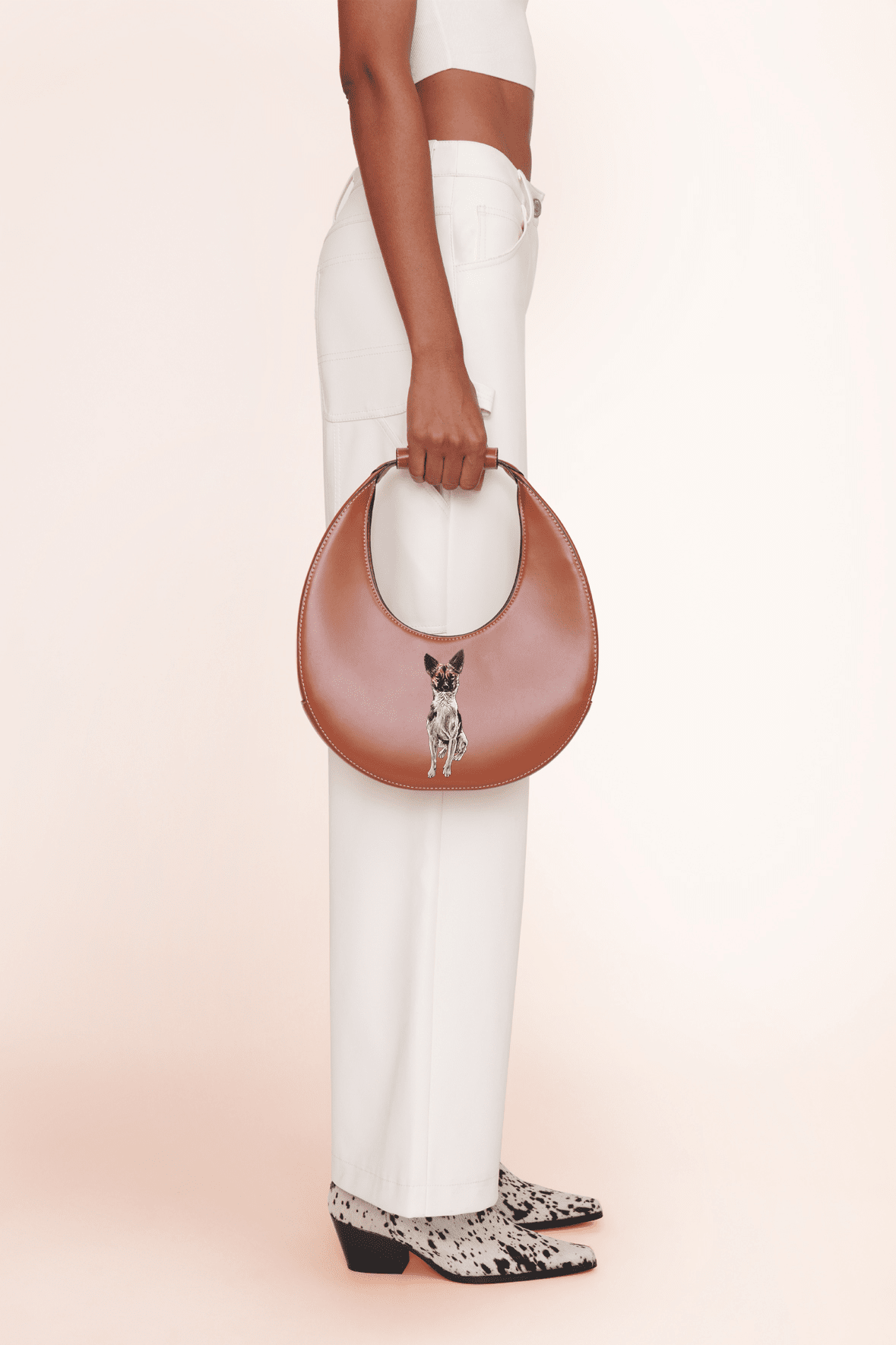 Tan crescent moon bag with front pet-face emblem and rounded top handle