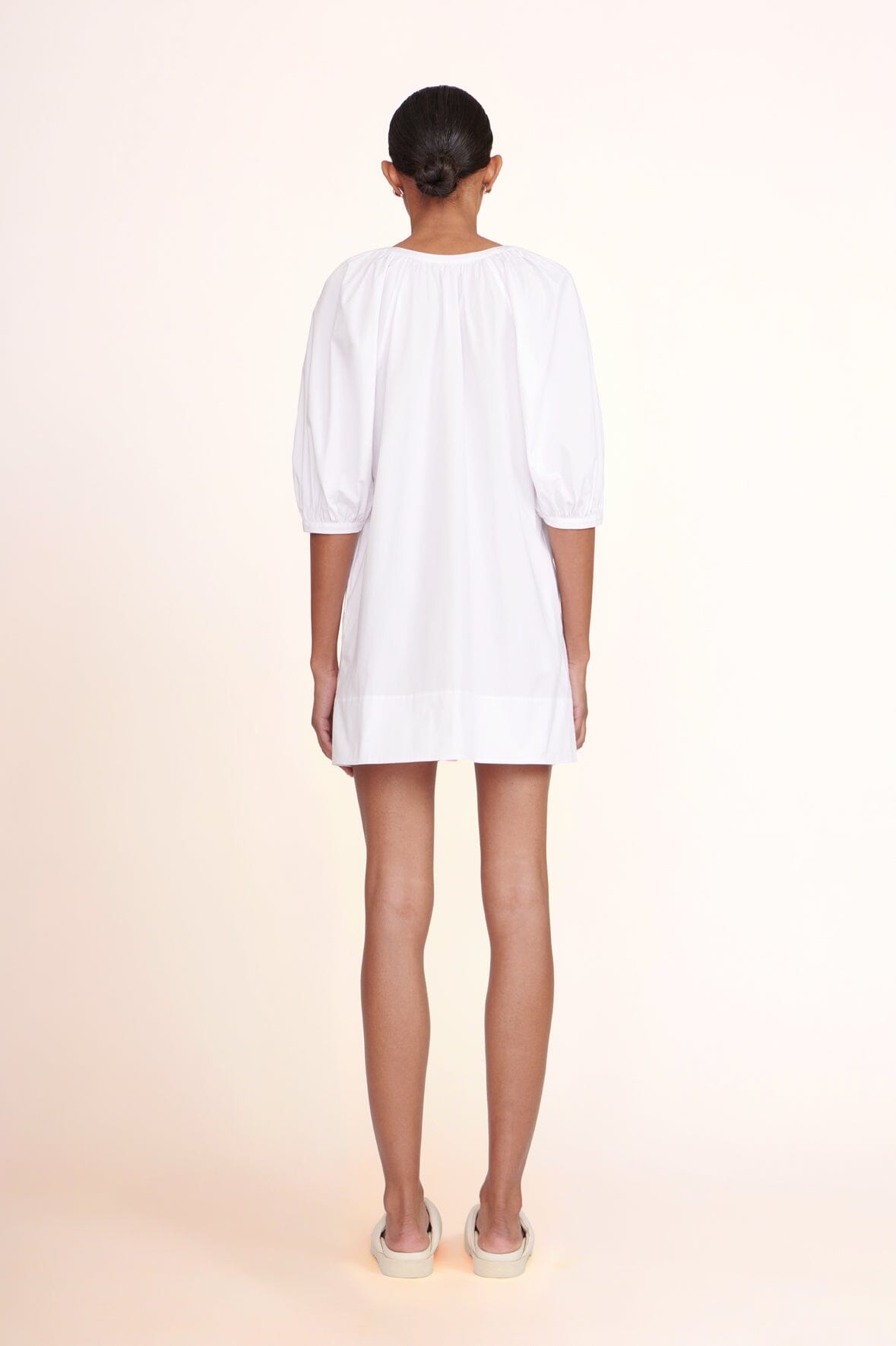 White mini dress back view with three-quarter puff sleeves and yoke gathers
