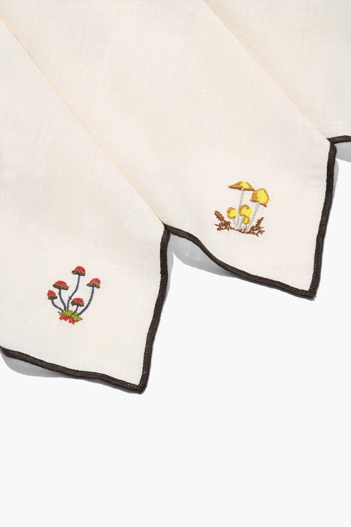 Natural embroidered napkins with black-trimmed edges and small corner motifs