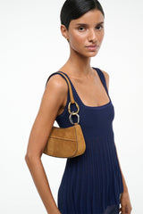 Tan suede hobo bag on model, gold-tone ring handle and shoulder strap
