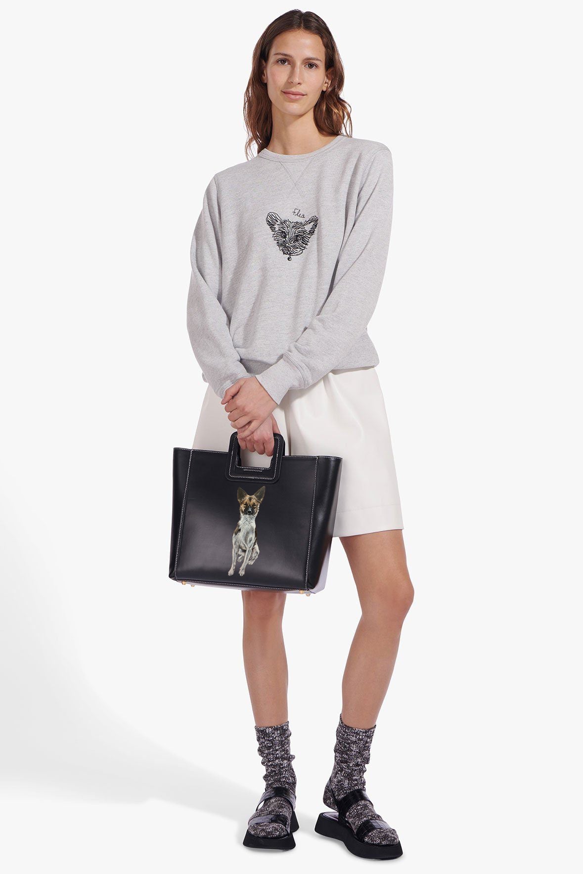 Black leather tote with top handle and dog portrait patch, worn on model