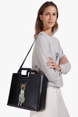 Black leather tote bag with front handle and dog portrait patch, side view