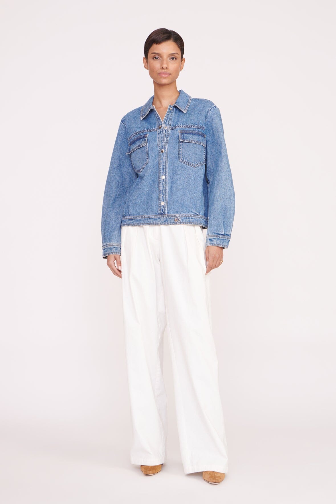 Medium-wash denim jacket on model with button front, flap chest pockets, long sleeves