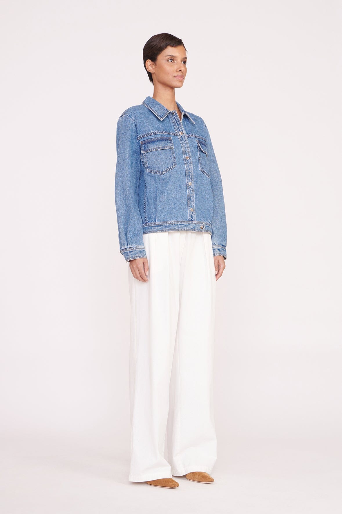 Medium-wash denim jacket on model from side with button front and chest flap pockets
