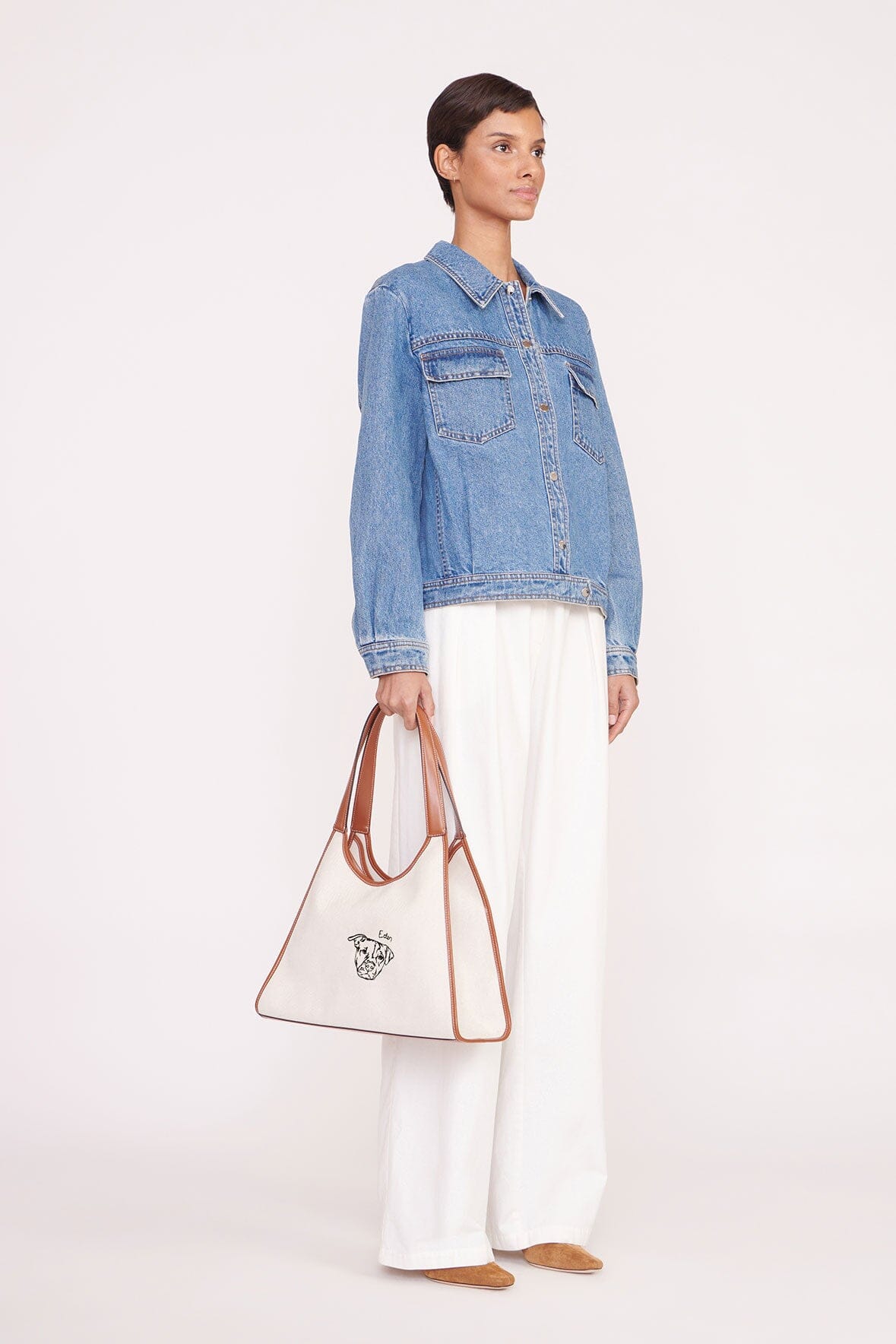 Cream canvas tote bag with tan leather handles and dog-face logo embroidery