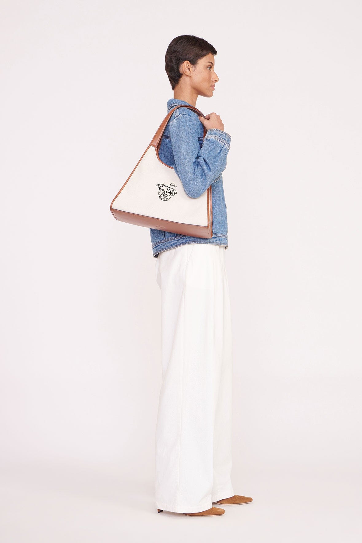 Cream canvas tote bag with tan leather handles and side edge seam