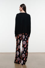 Silk pants in black with colorful circular paisley print, side view, wide leg