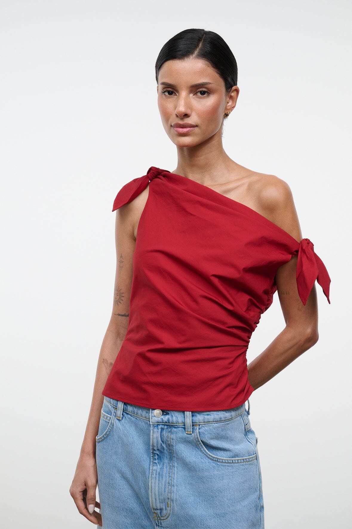 Red one-shoulder draped top with shoulder bow ties and gathered side ruching.