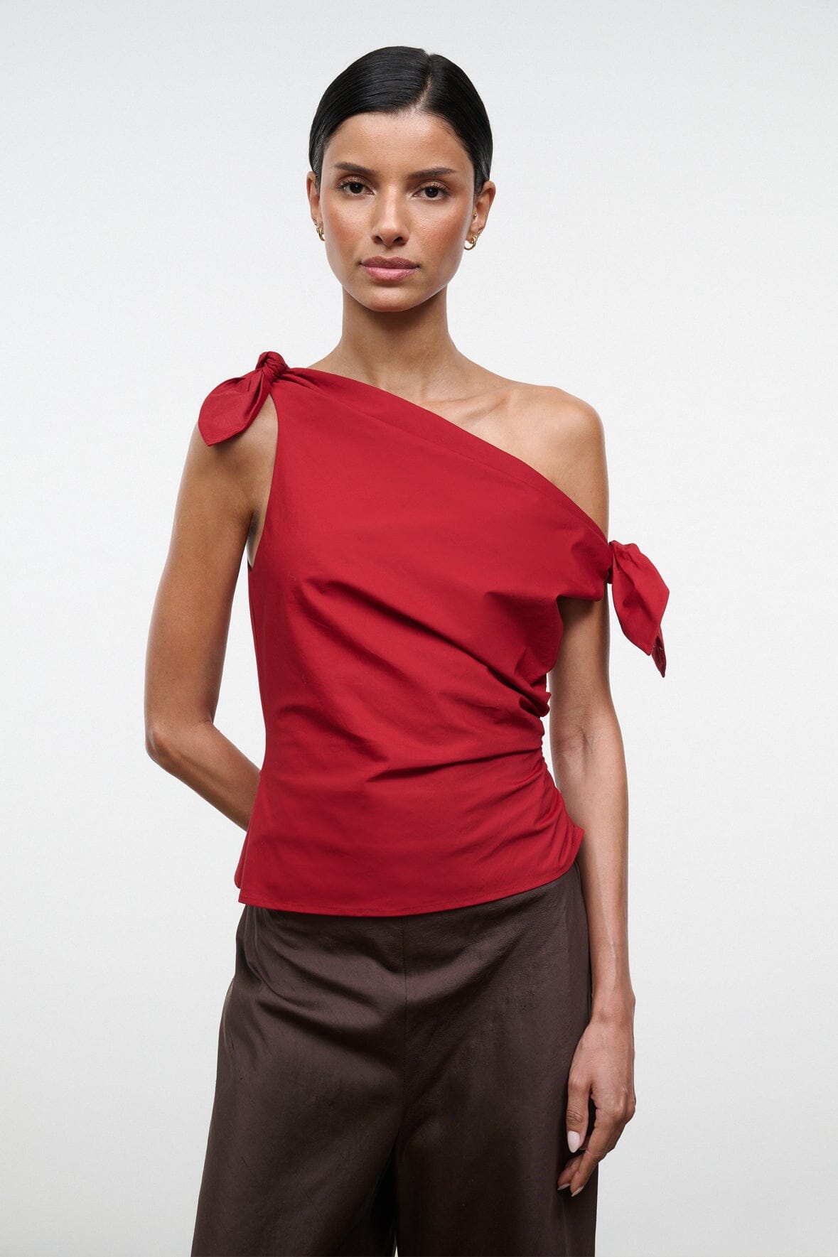 Red one-shoulder draped top with bow tie at shoulder and gathered drape at waist.