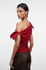 Side view of red asymmetrical one-shoulder draped top with shoulder bow ties.