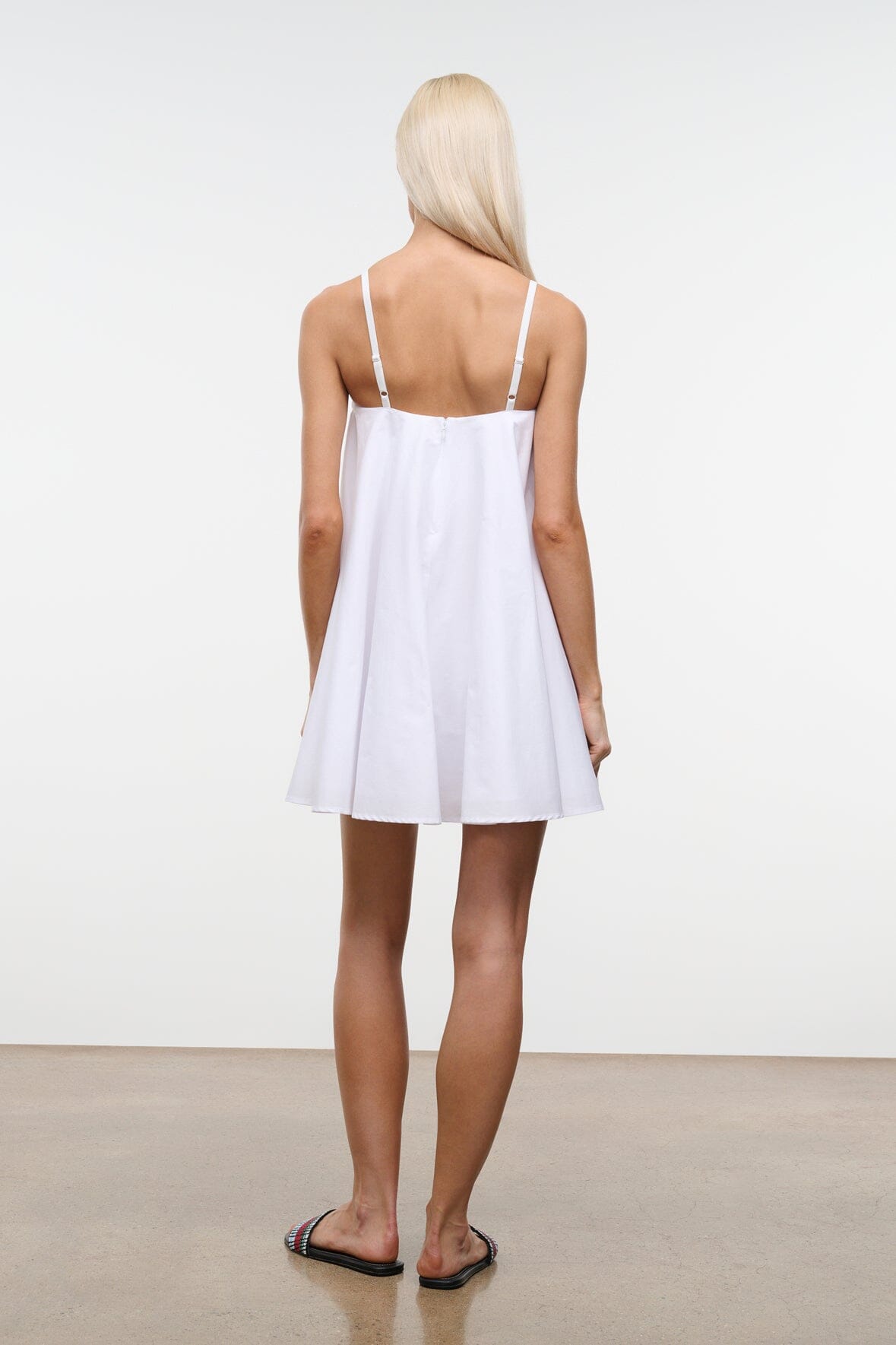 White mini dress, back view, with spaghetti straps and gathered waist.