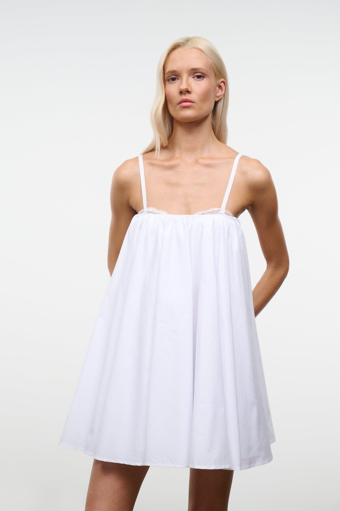 White mini dress with spaghetti straps, gathered bust, and flouncy skirt.