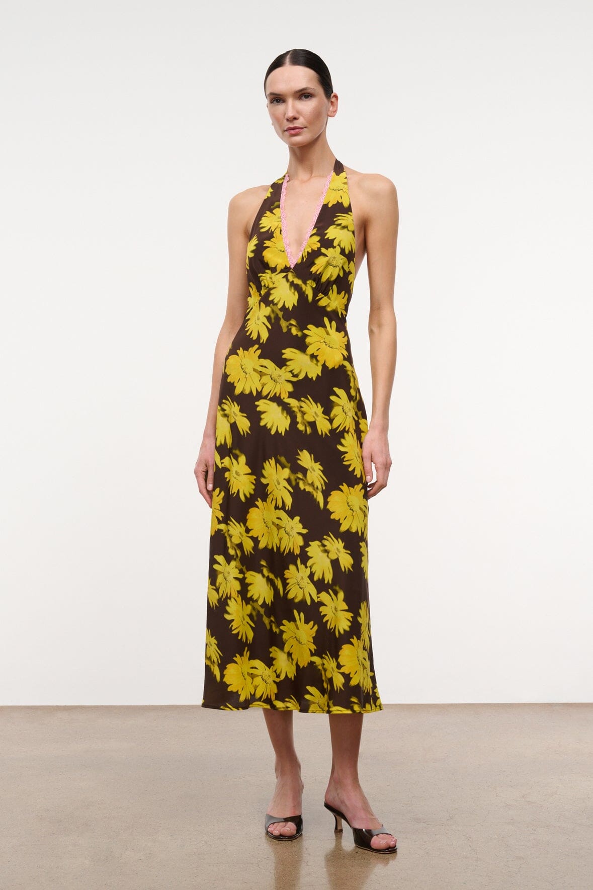Front view halter midi dress with yellow daisy motif on dark background and V neckline.