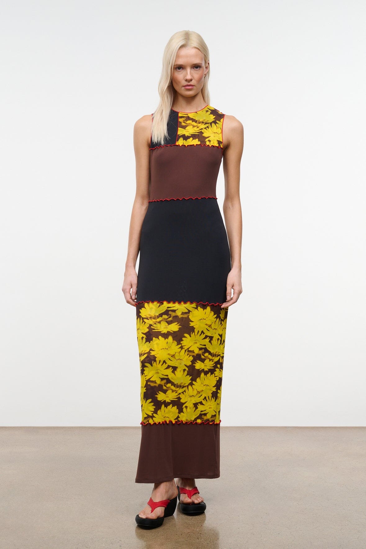 PRIMO sleeveless dress in black, brown, and yellow daisy print with red-trim seams