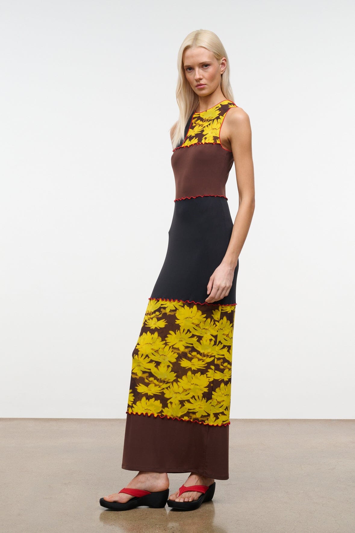PRIMO sleeveless dress side view, black bodice with brown panel and yellow daisy skirt