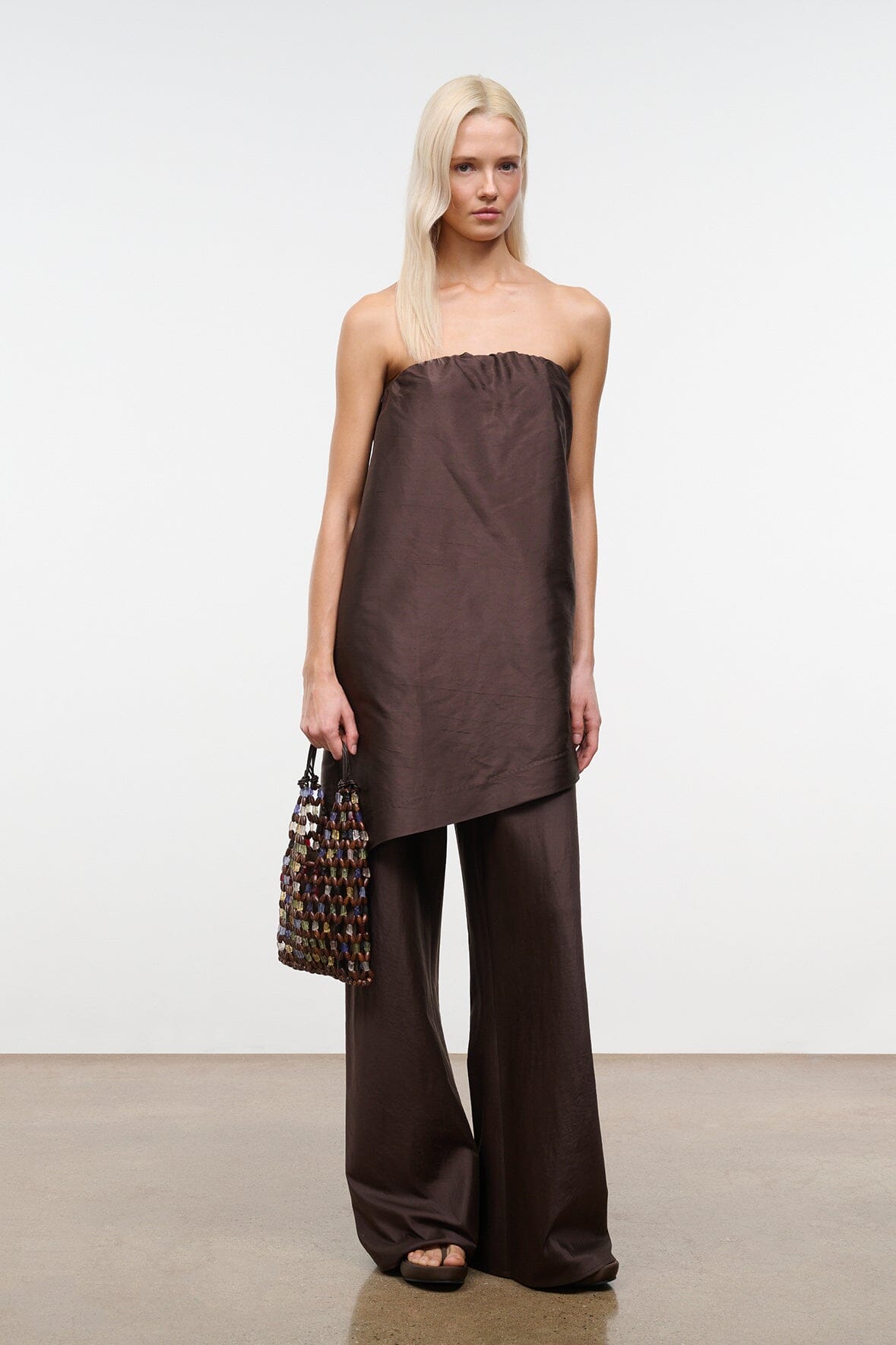 Dark brown strapless top with gathered neckline and side-slit asymmetrical drape