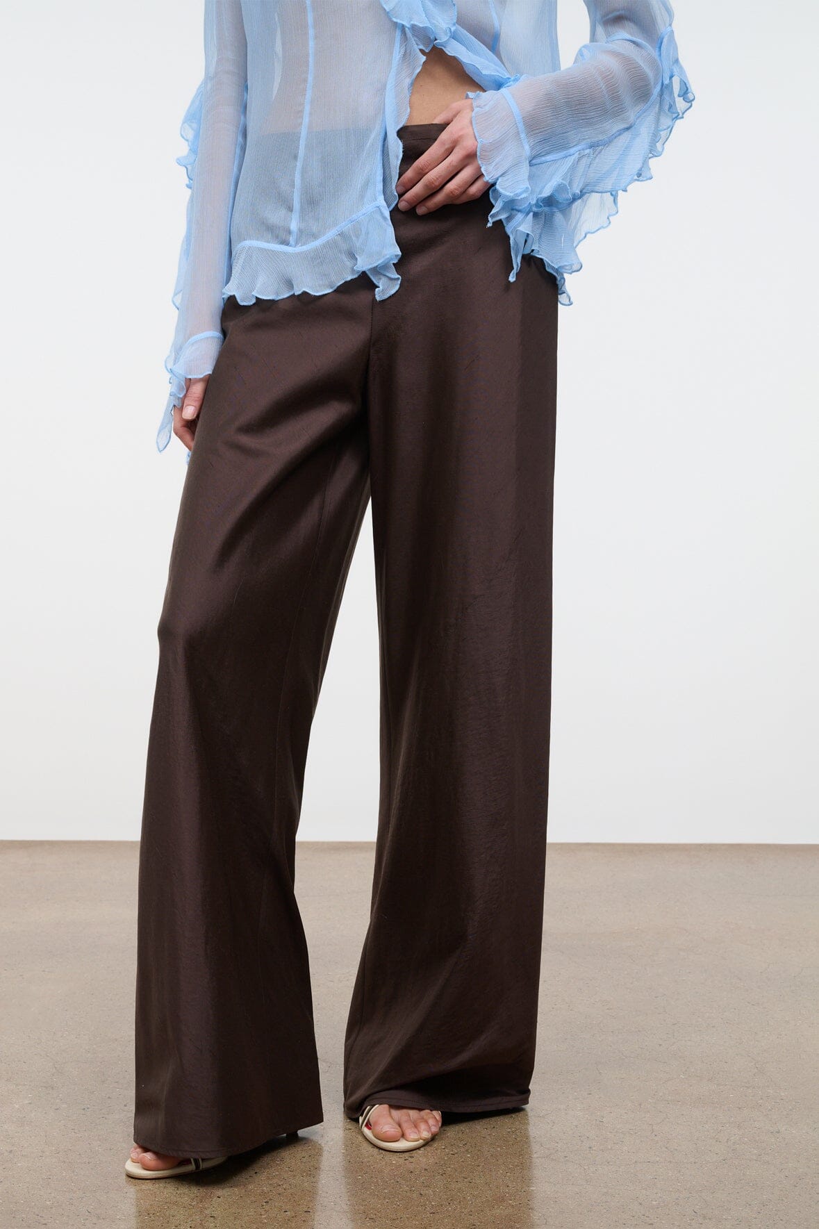 Dark brown wide-leg pants with smooth front and relaxed straight-leg silhouette