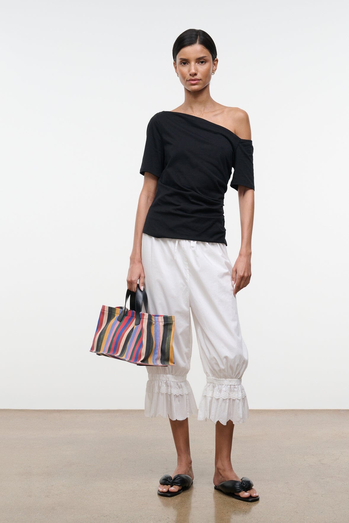 Black Carine top with diagonal off-shoulder neckline and short sleeves, side front view