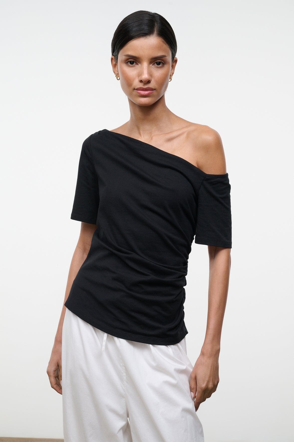 Black Carine top with draped diagonal off-shoulder neckline and short sleeves, front