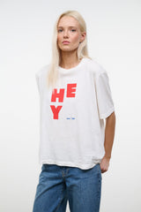White relaxed tee with red “HEY” print; neckline and short sleeves visible.
