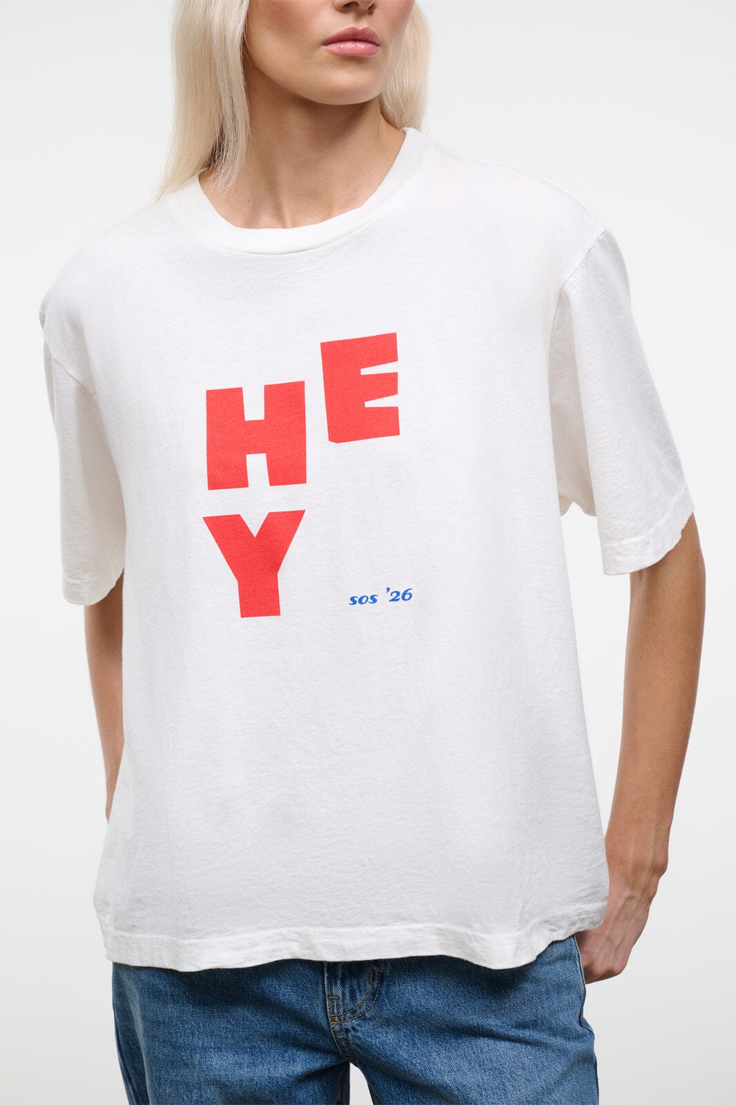 White relaxed tee with red “HEY” logo and small blue “so’s ’26” text; short sleeves.