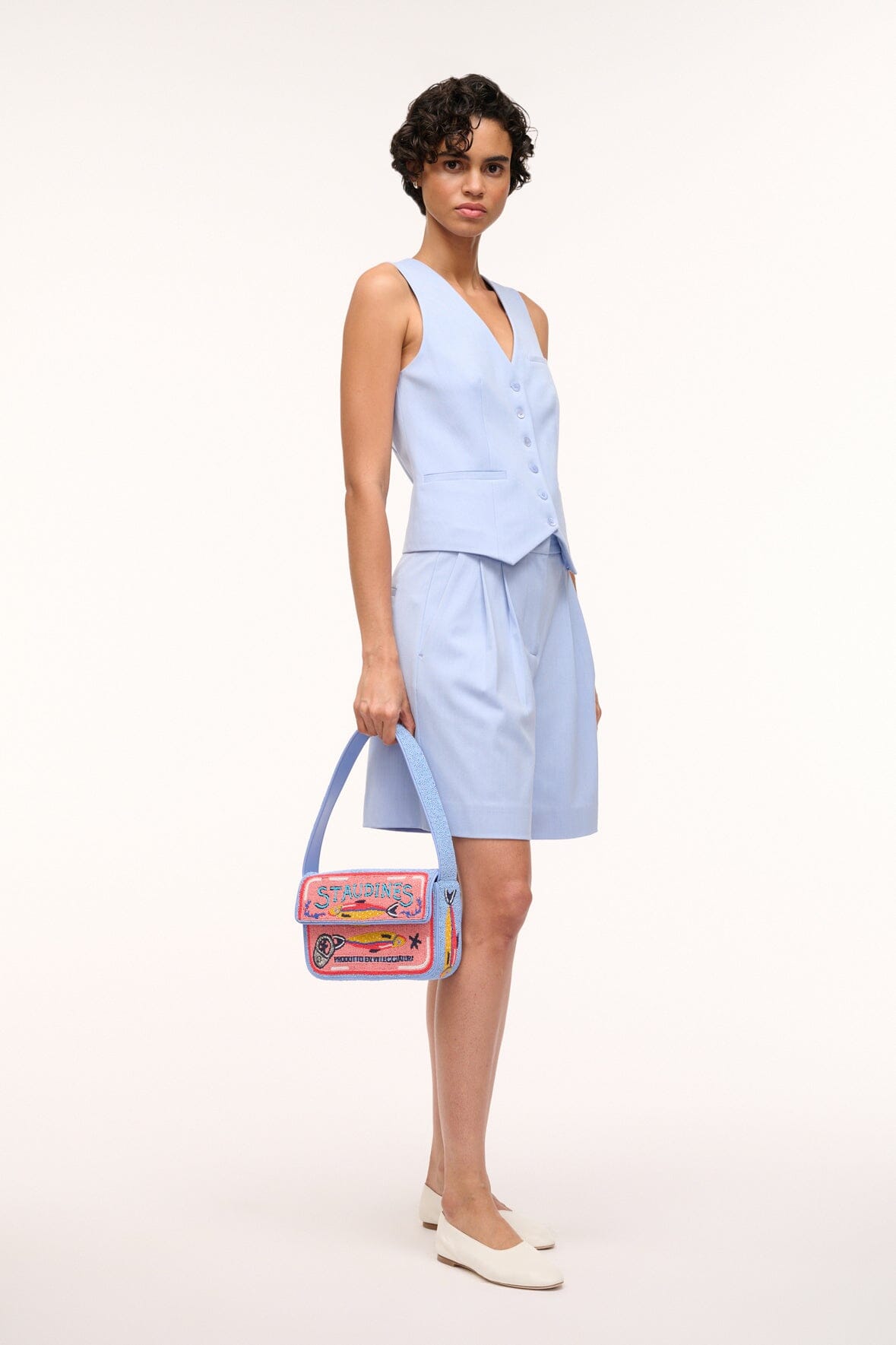 Model holding a light blue beaded mini bag with colorful embroidered front