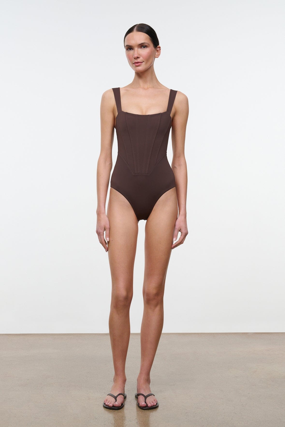 Dark one-piece swimsuit, square neckline, thin straps, high-leg cut