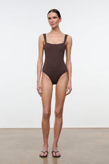 Dark one-piece swimsuit, square neckline, thin straps, high-leg cut