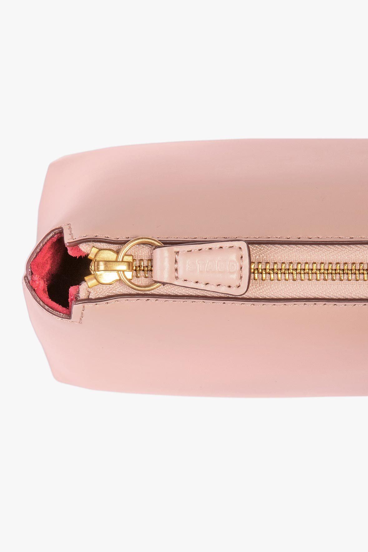 Blush leather mini tote bag closeup with gold zipper and red interior
