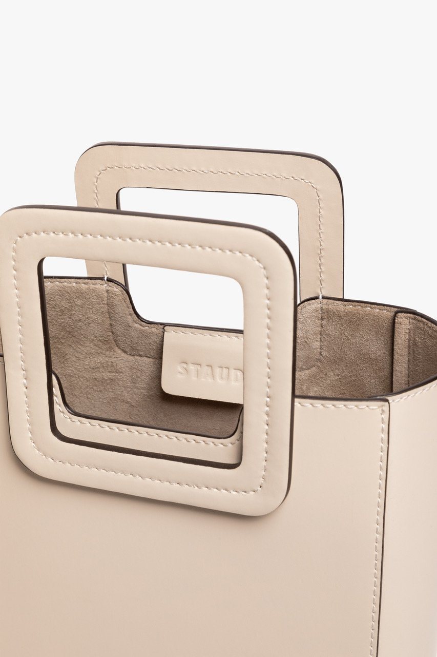 Mini cream leather bag interior view through front cutout, logo patch inside