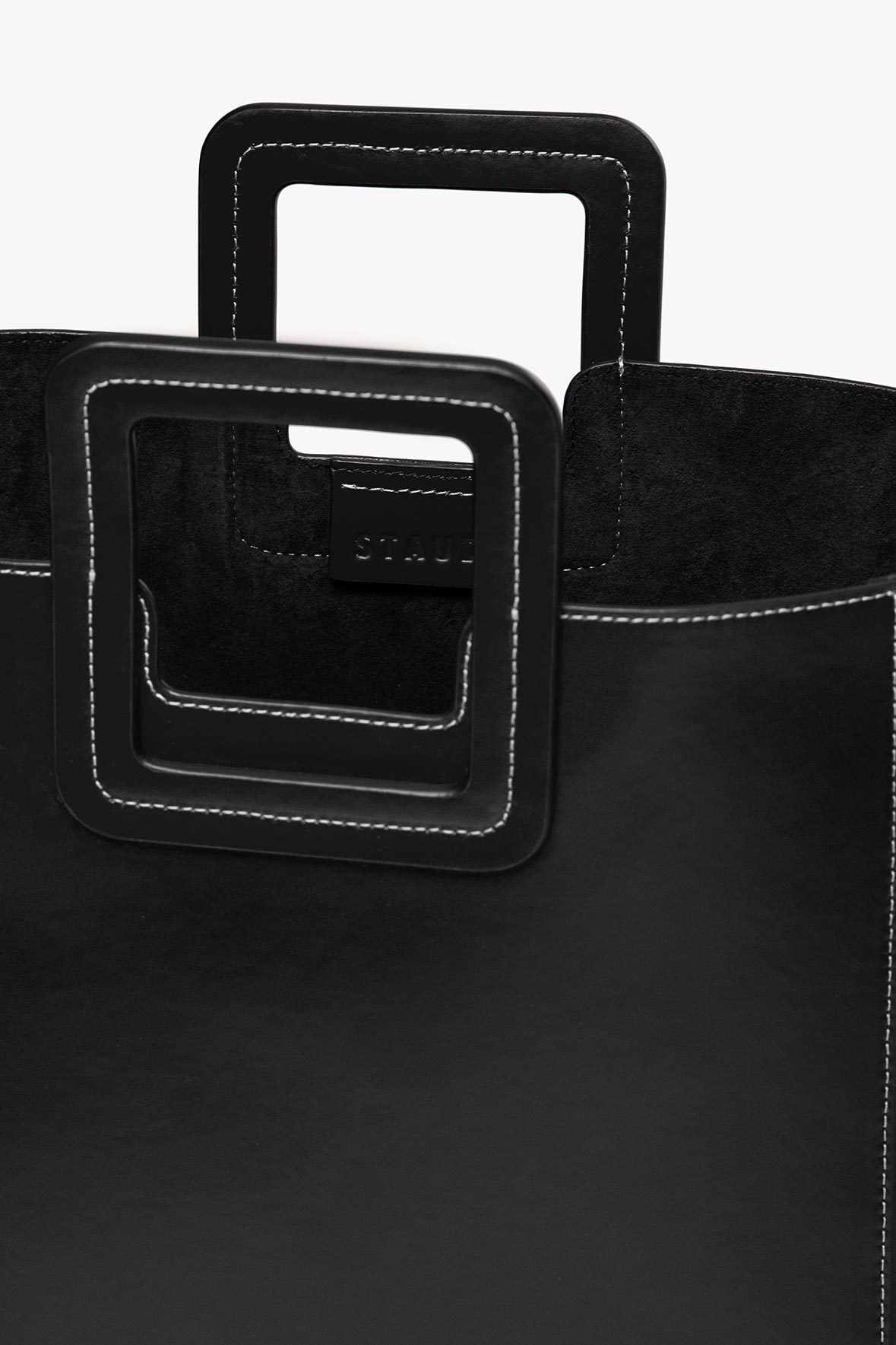 Black leather tote bag with layered handle frames and stitched detailing