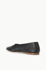 Black ballet flat showing heel and rounded toe, tan outsole