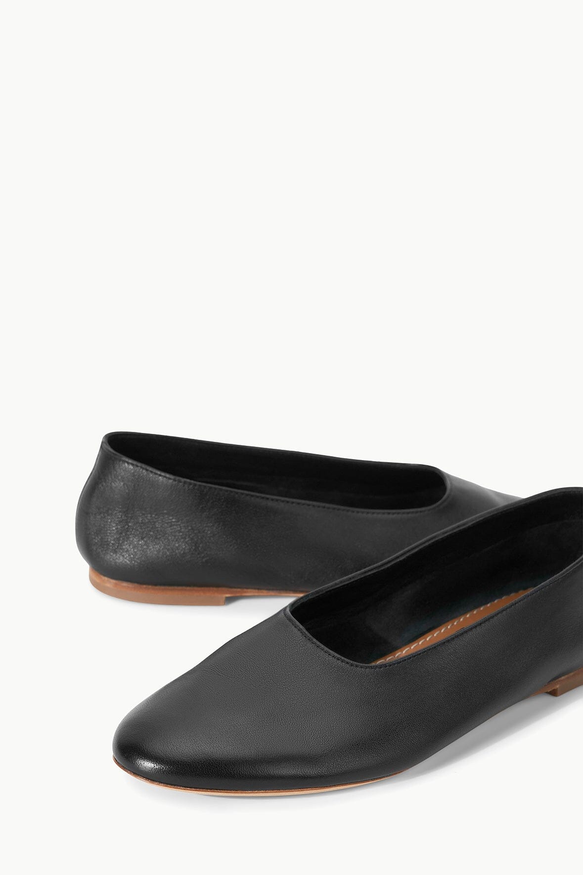 Black ballet flats with rounded toe, slip-on design, tan outsole edge