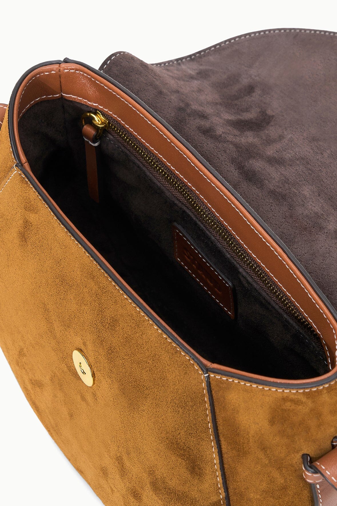 Tan suede saddle bag interior view with brown trim and stitched edge detail.