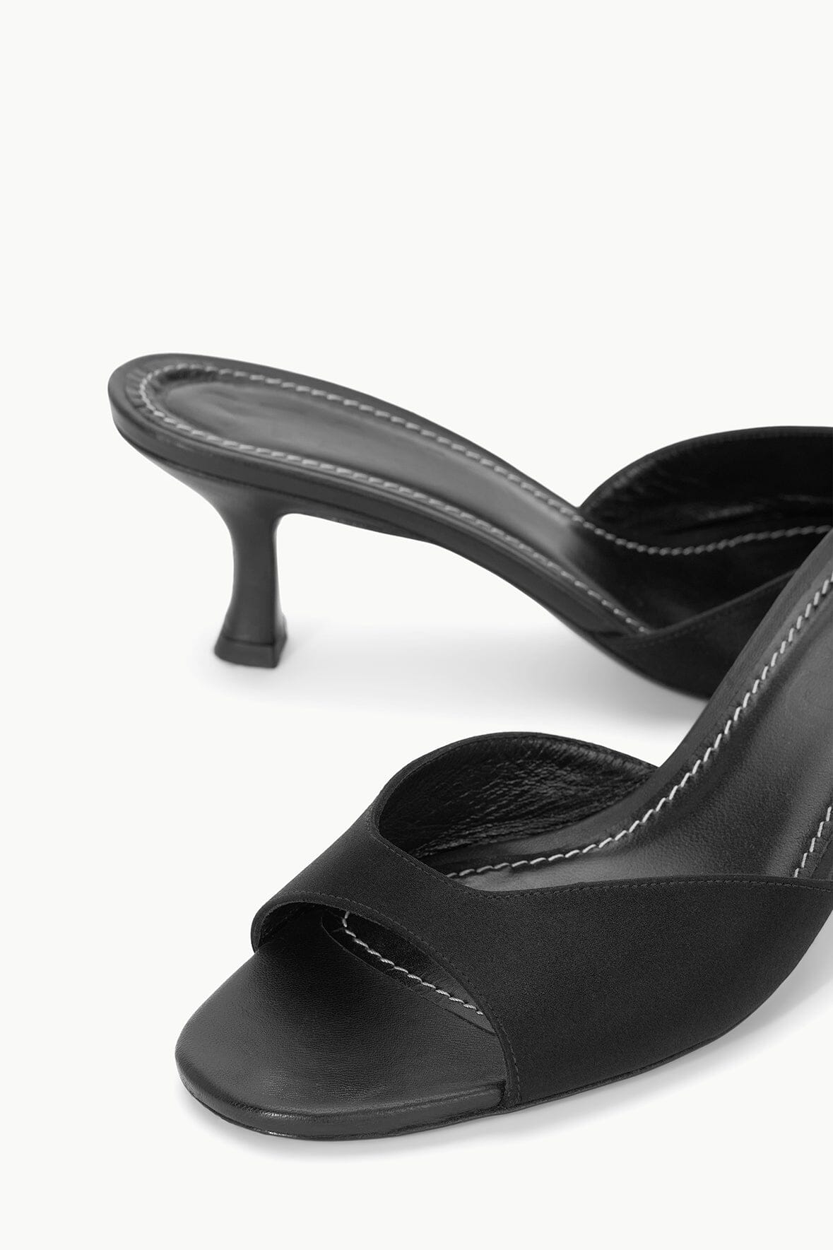 Close-up of black satin mule upper with stitched thong and sculpted heel