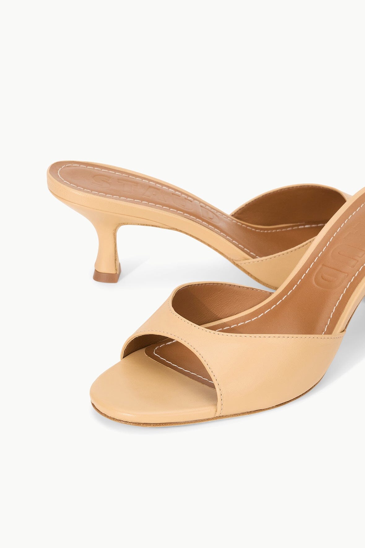 Tan leather heeled mule with open toe, sling strap detail, and block heel.